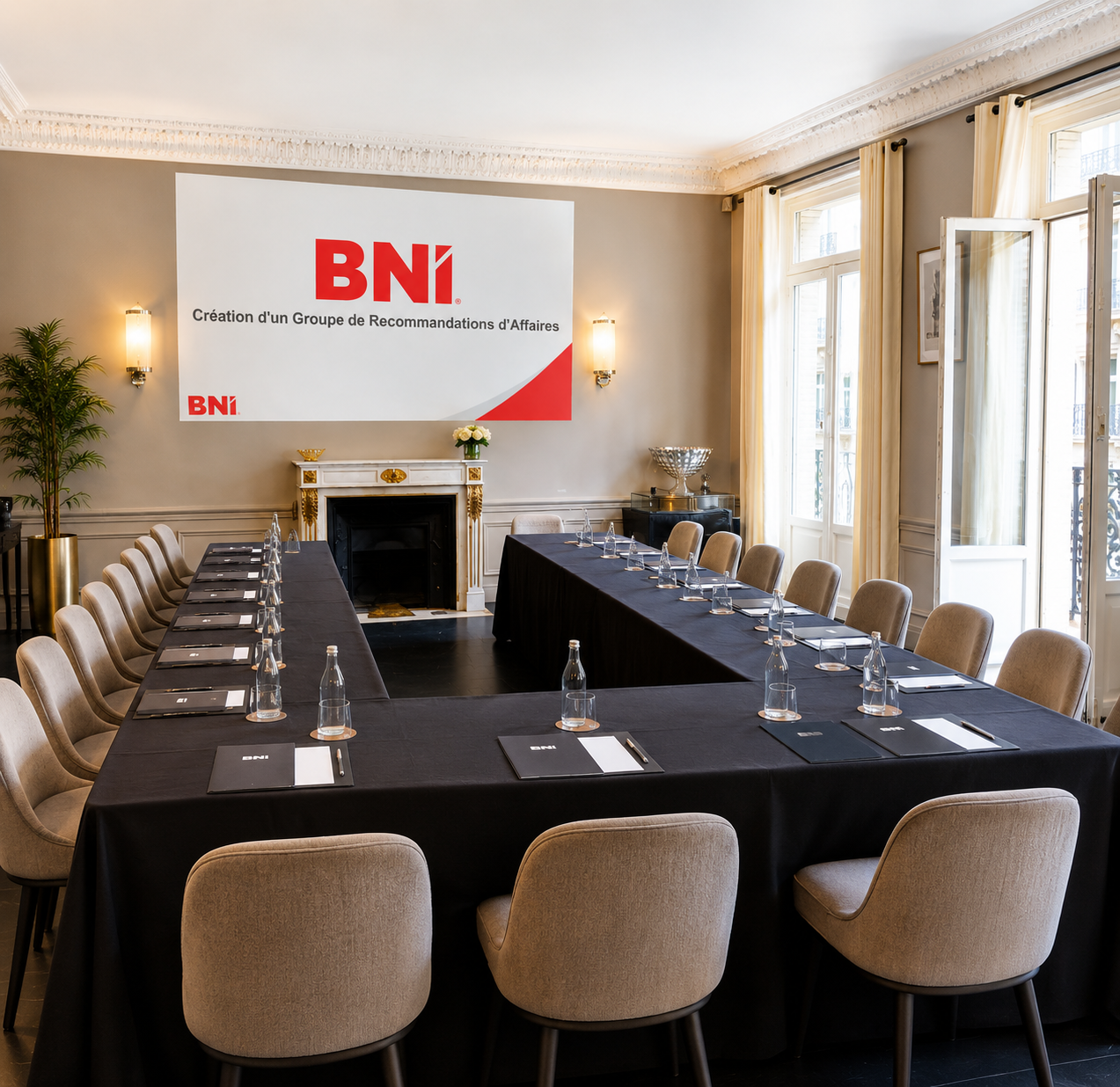 Séminaire d'entreprise au Loft Triangle d'Or — configuration en U avec tables nappées noires, fauteuils contemporains et écran de présentation devant la cheminée haussmannienne