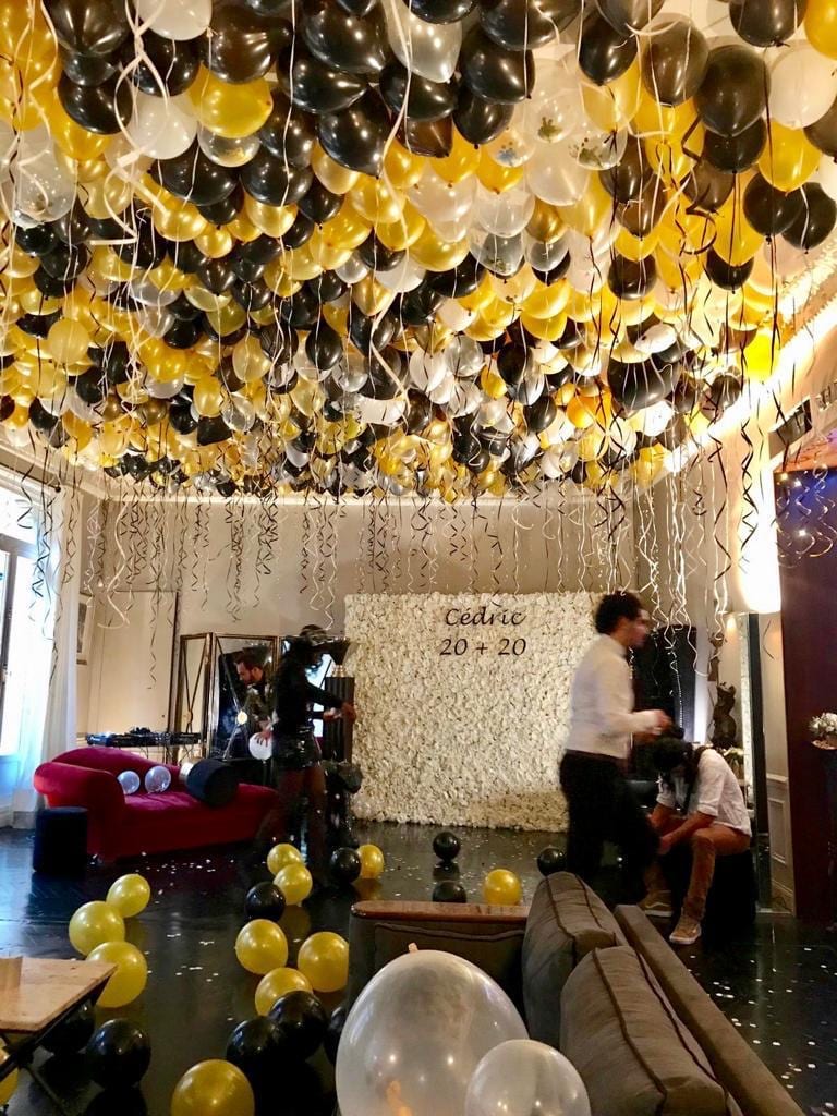 Plafond couvert de ballons or, noirs et blancs avec mur de fleurs