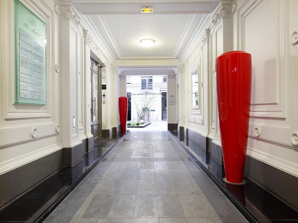 Couloir d'entrée du 18 rue Marbeuf — pierre, vases écarlates et moulures classiques