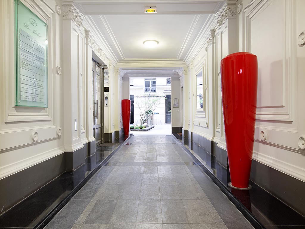 Couloir d'entrée du 18 rue Marbeuf — pierre, vases écarlates et moulures classiques