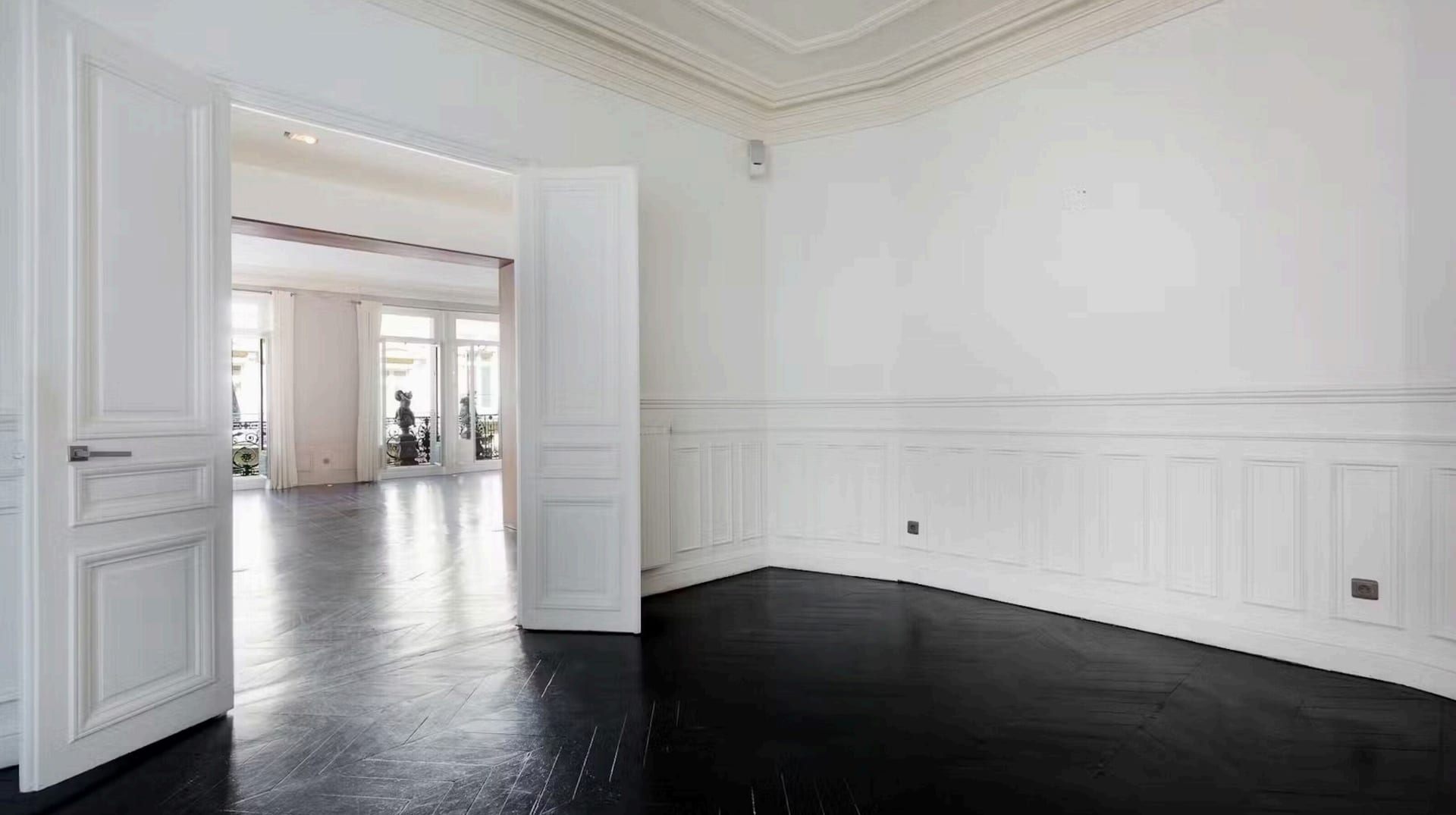 Enfilade de salons aux parquets chevron noirs et boiseries blanches